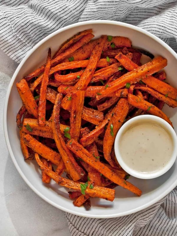 Baked carrot fries with tahini sauce in a bowl.