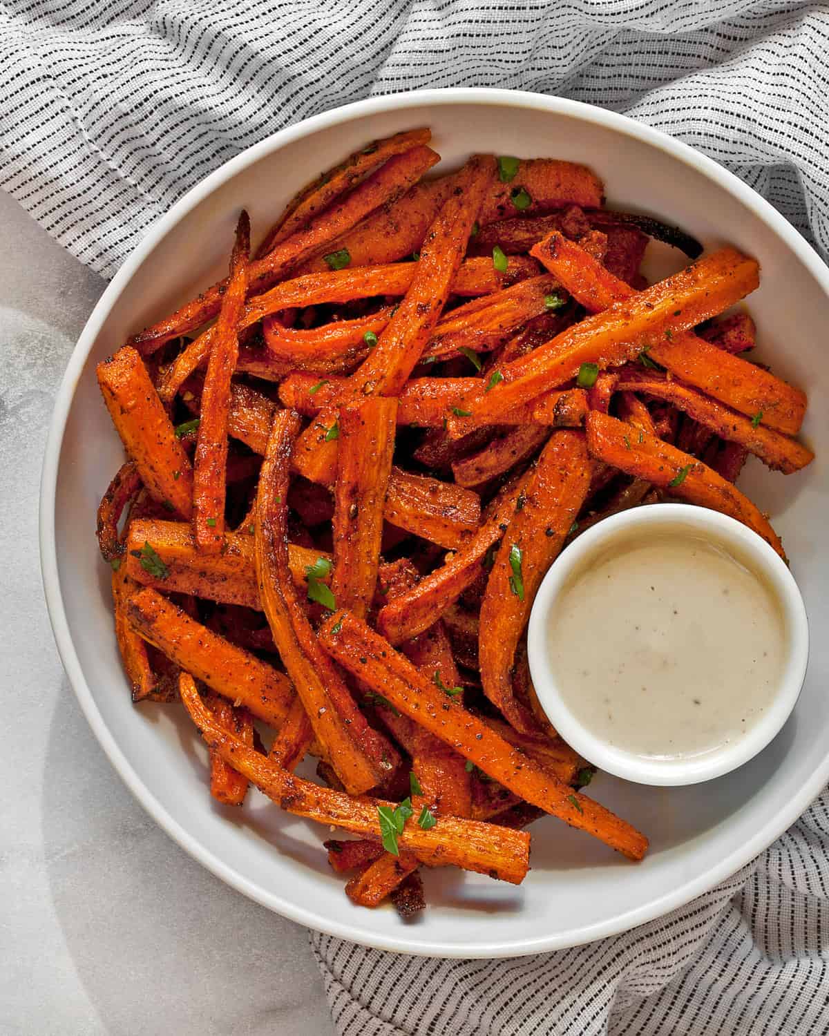 Baked carrot fries with tahini sauce in a bowl.