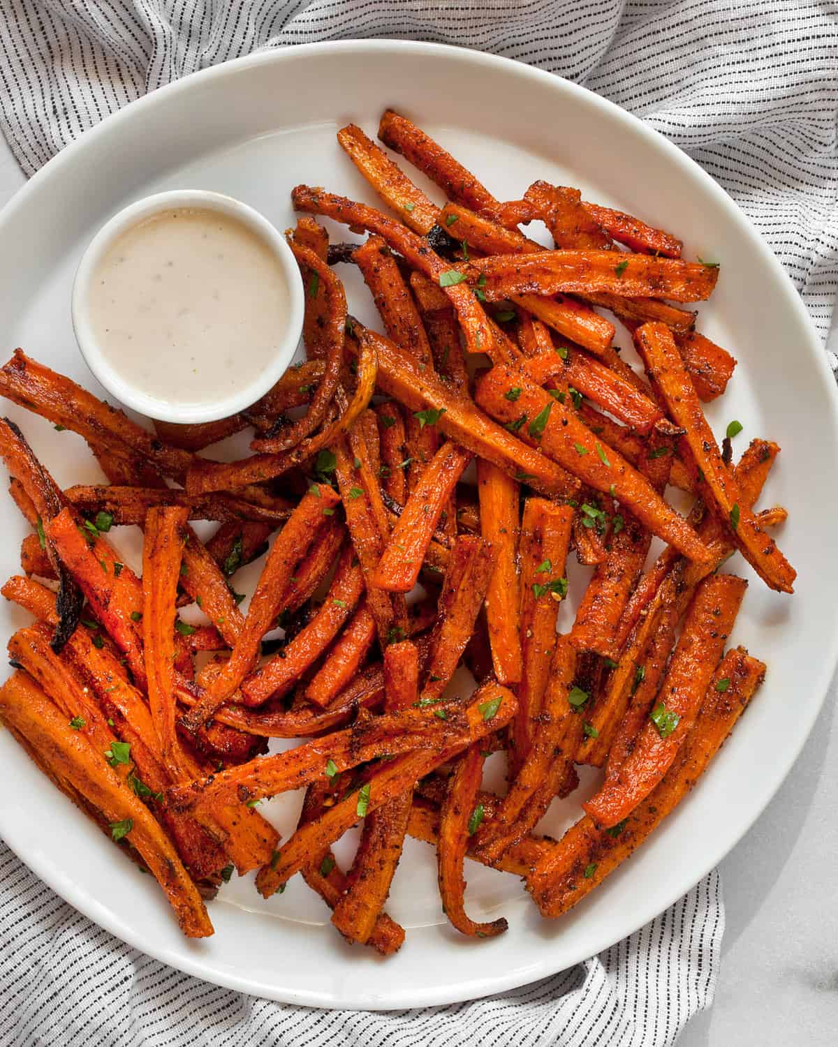 Healthy baked fries on a plate with tahini dipping sauce.