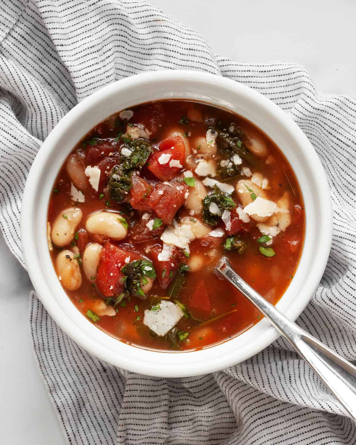 White bean soup with tomatoes and kale in a bowl.