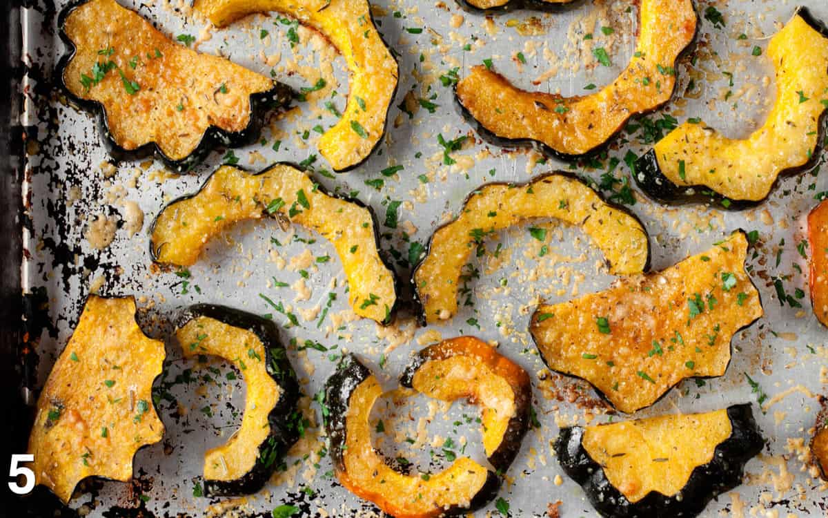 Roasted squash on a sheet pan sprinkled with fresh herbs.