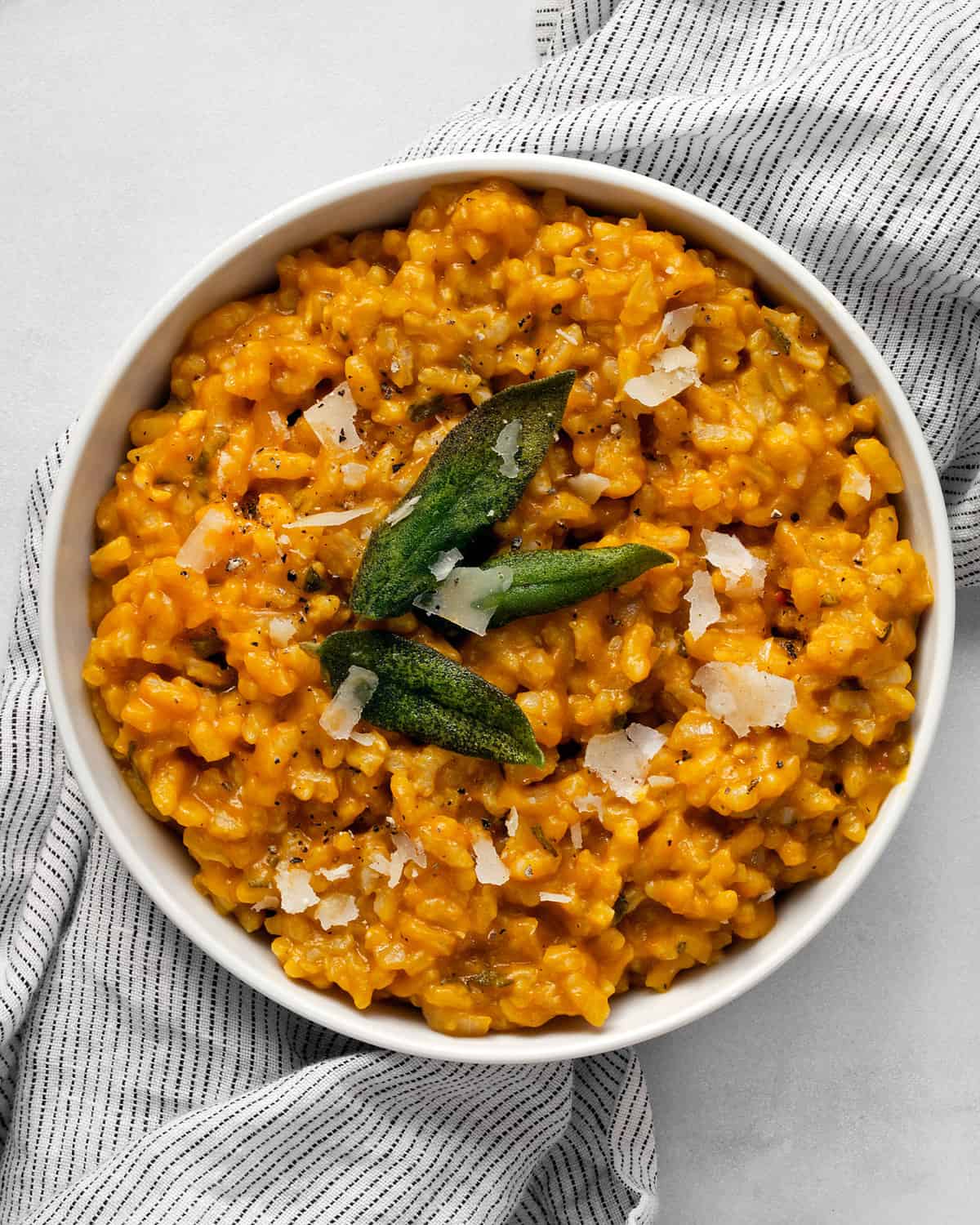 Pumpkin risotto topped with crispy sage in a bowl.