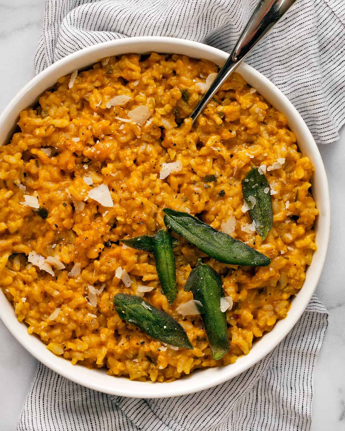 Pumpkin risotto in a bowl with a serving spoon.