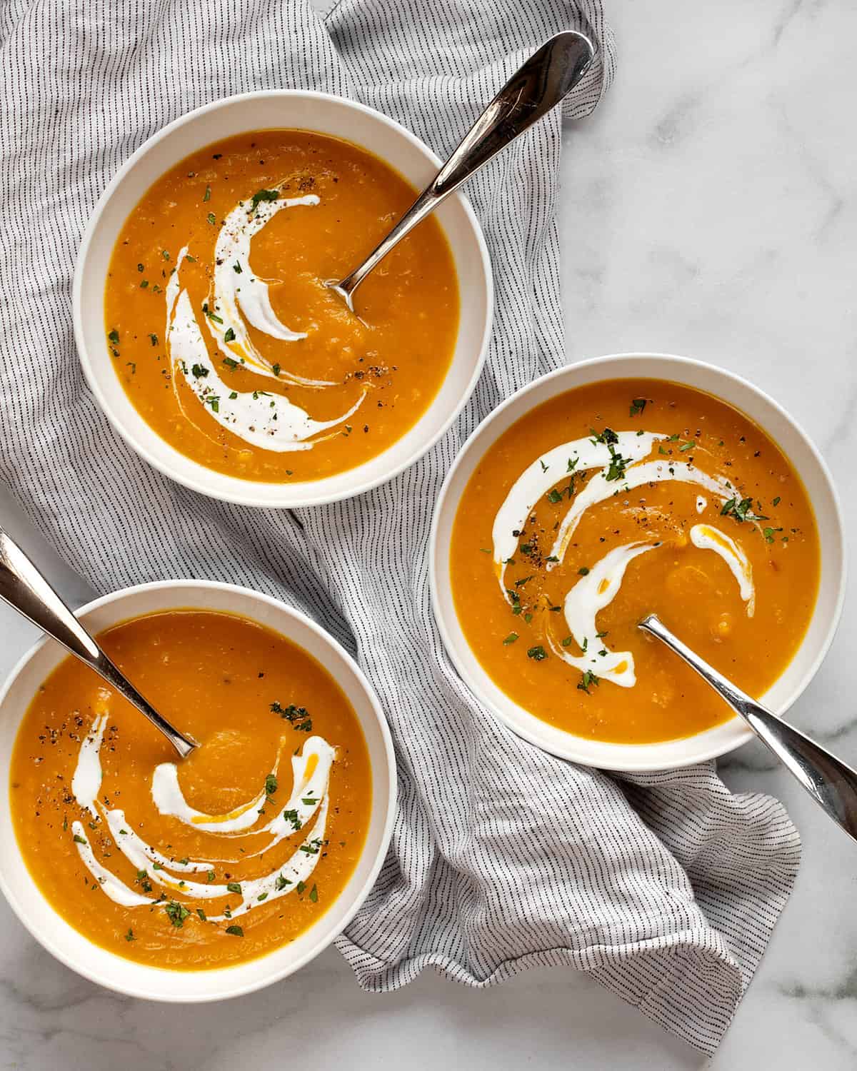 Three bowls of butternut squash apple soup.