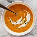 Bowl of butternut squash apple soup with a yogurt swirl.