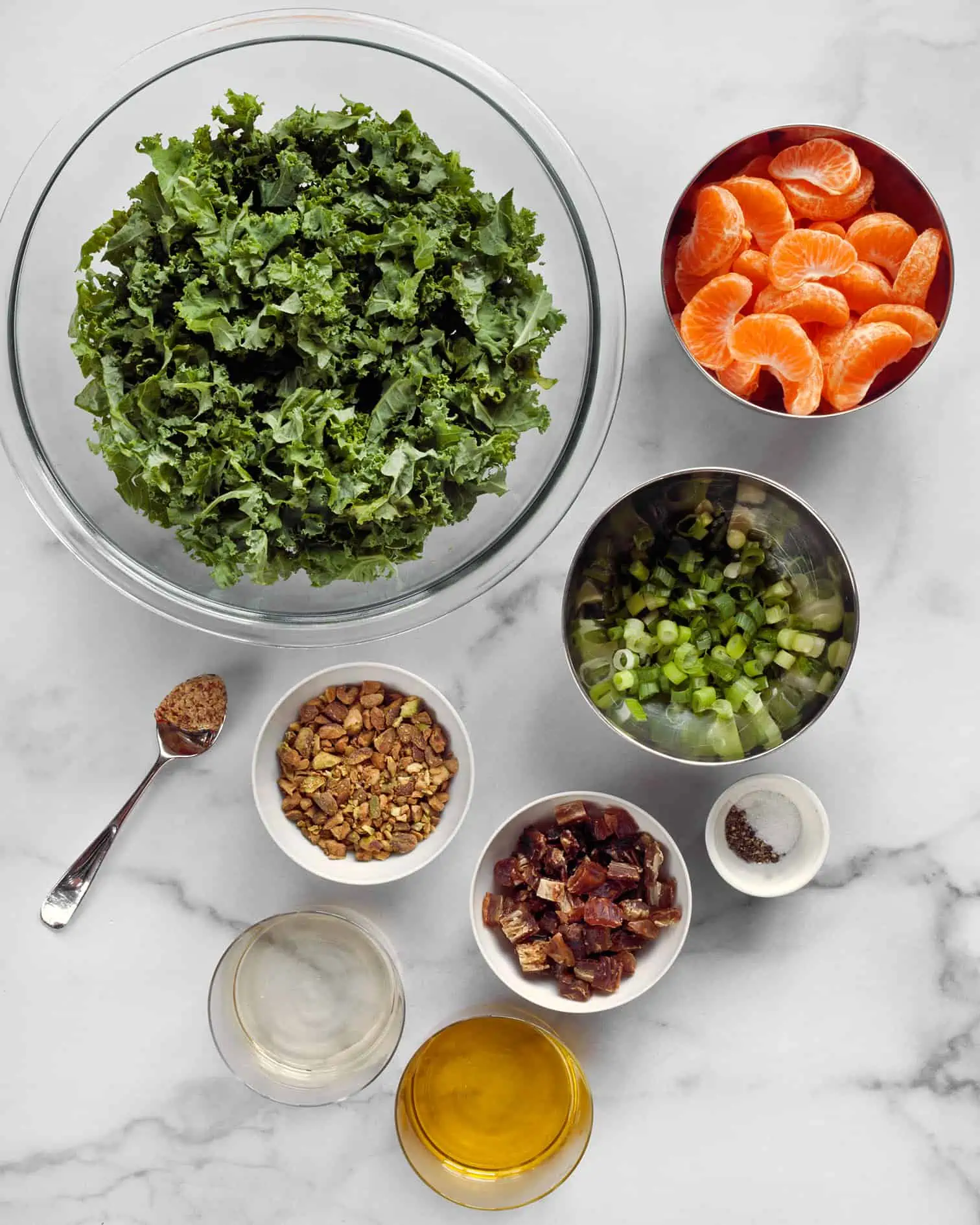 Ingredients for kale salad including mandarin oranges, dates, pistachios, and scallions