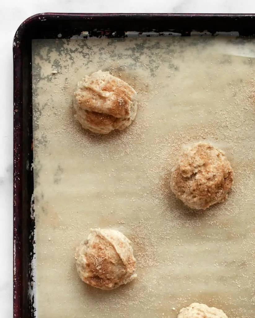 Portioning out scone dough on sheet pan and sprinkling with cinnamon sugar