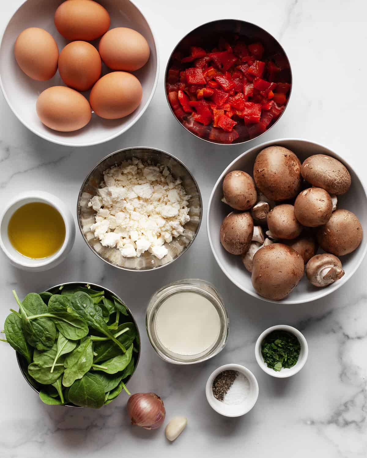 Ingredients including eggs, milk, mushrooms, peppers, shallots, feta, spinach, olive oil, salt and pepper.