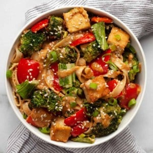 Tofu vegetable stir-fry drizzled with peanut sauce in a bowl.