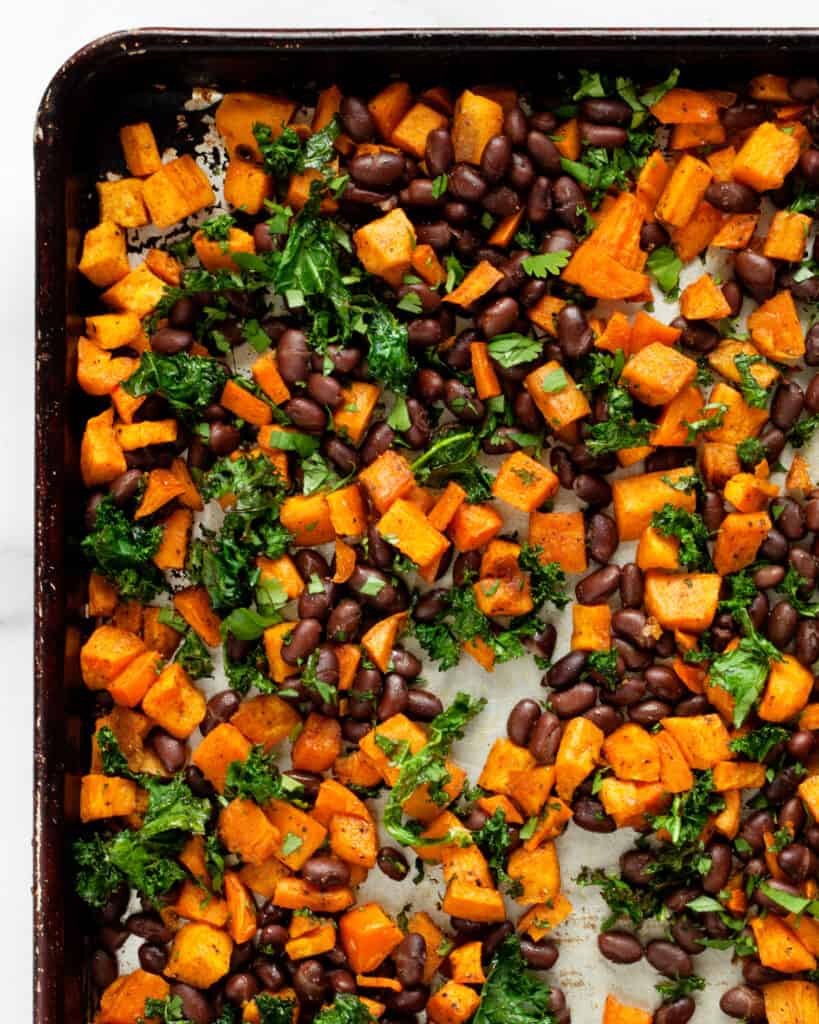 Roasted sweet potatoes on a sheet pan with black beans, cilantro and kale