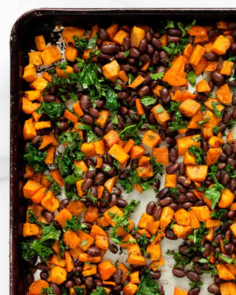 Roasted sweet potatoes on a sheet pan with black beans, cilantro and kale