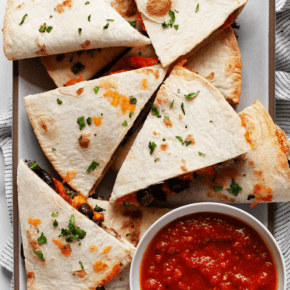 Roasted sweet potato black bean quesadillas cut into wedges on a plate.