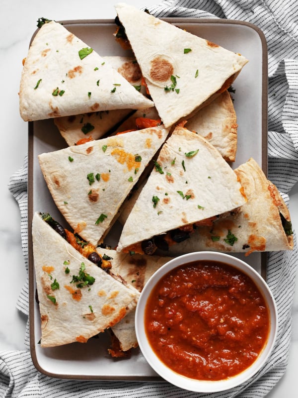 Roasted sweet potato black bean quesadillas cut into wedges on a plate.