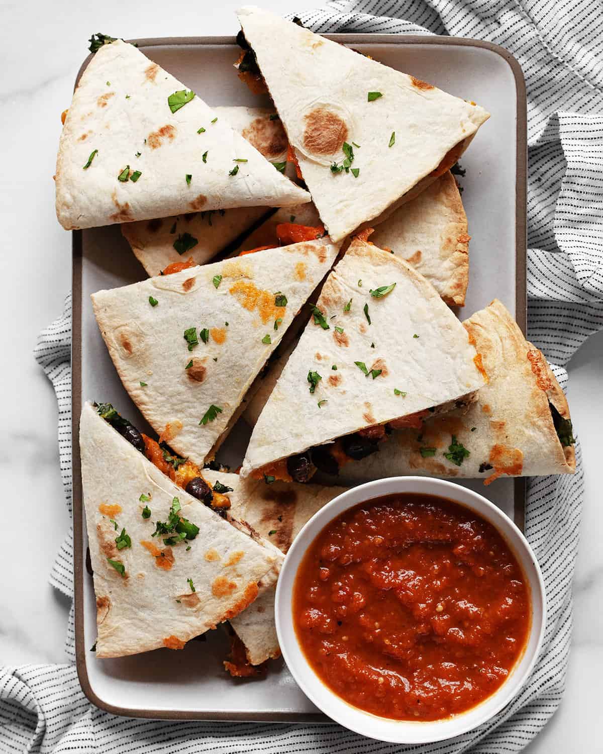 Roasted sweet potato black bean quesadillas cut into wedges on a plate.