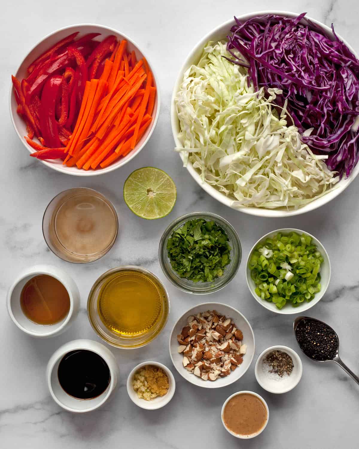 Ingredients including cabbage, carrots, peppers, cilantro, almonds, olive oil, soy sauce, sesame seeds, ginger and garlic.