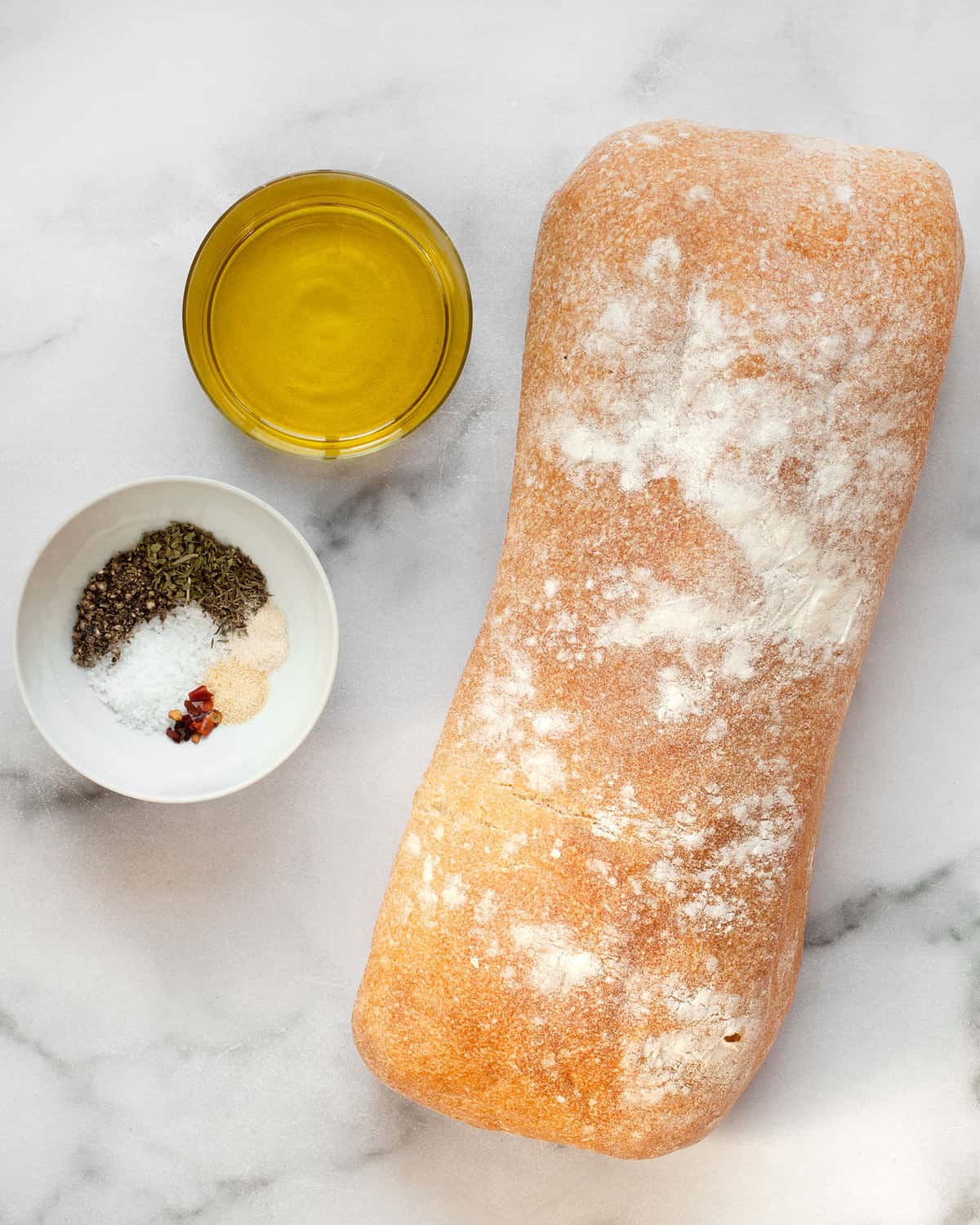 Ingredients including loaf of bread, olive oil and dried spices.