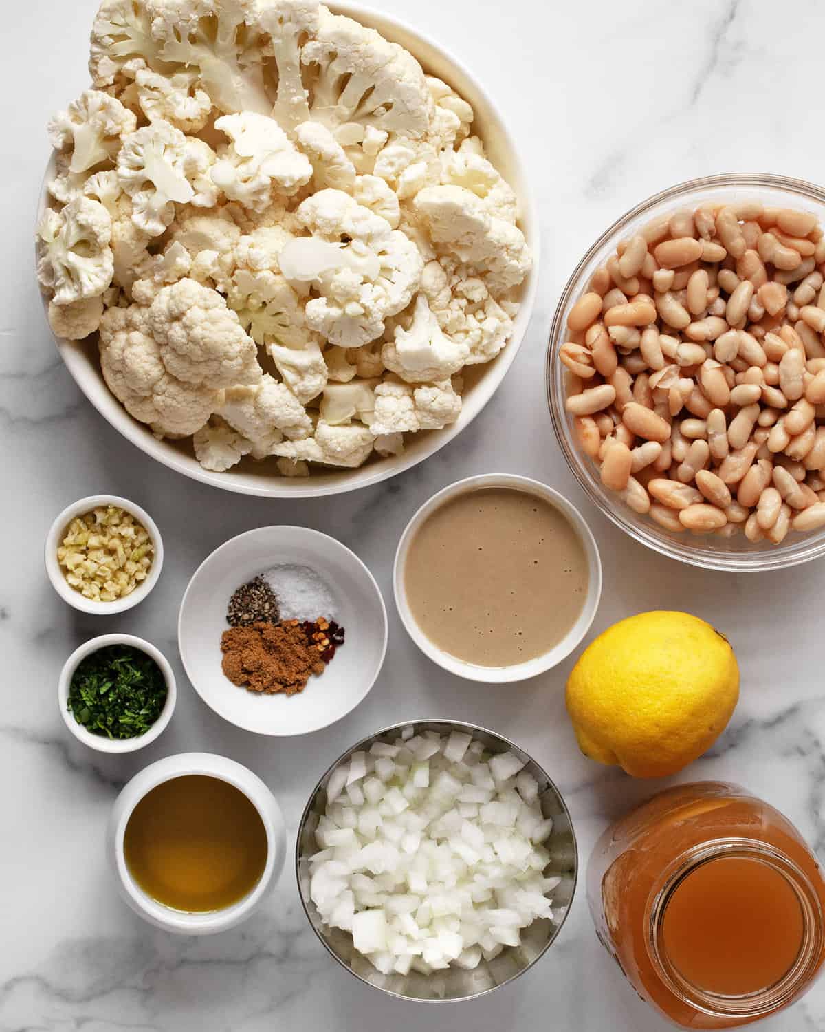 Ingredients including cauliflower, cannellini beans, tahini, spices, veggie broth, garlic and onions.