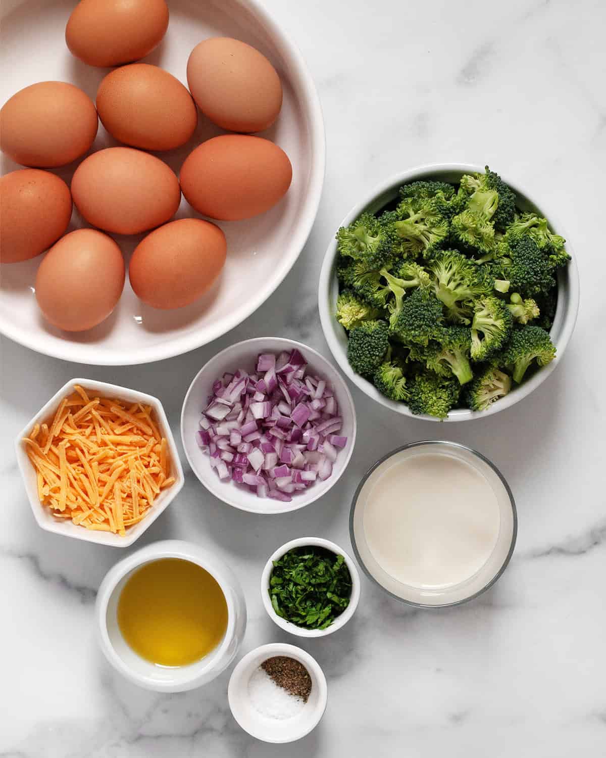 Ingredients including eggs, broccoli, red onions, cheddar, milk, olive oil, parsley, salt and pepper.