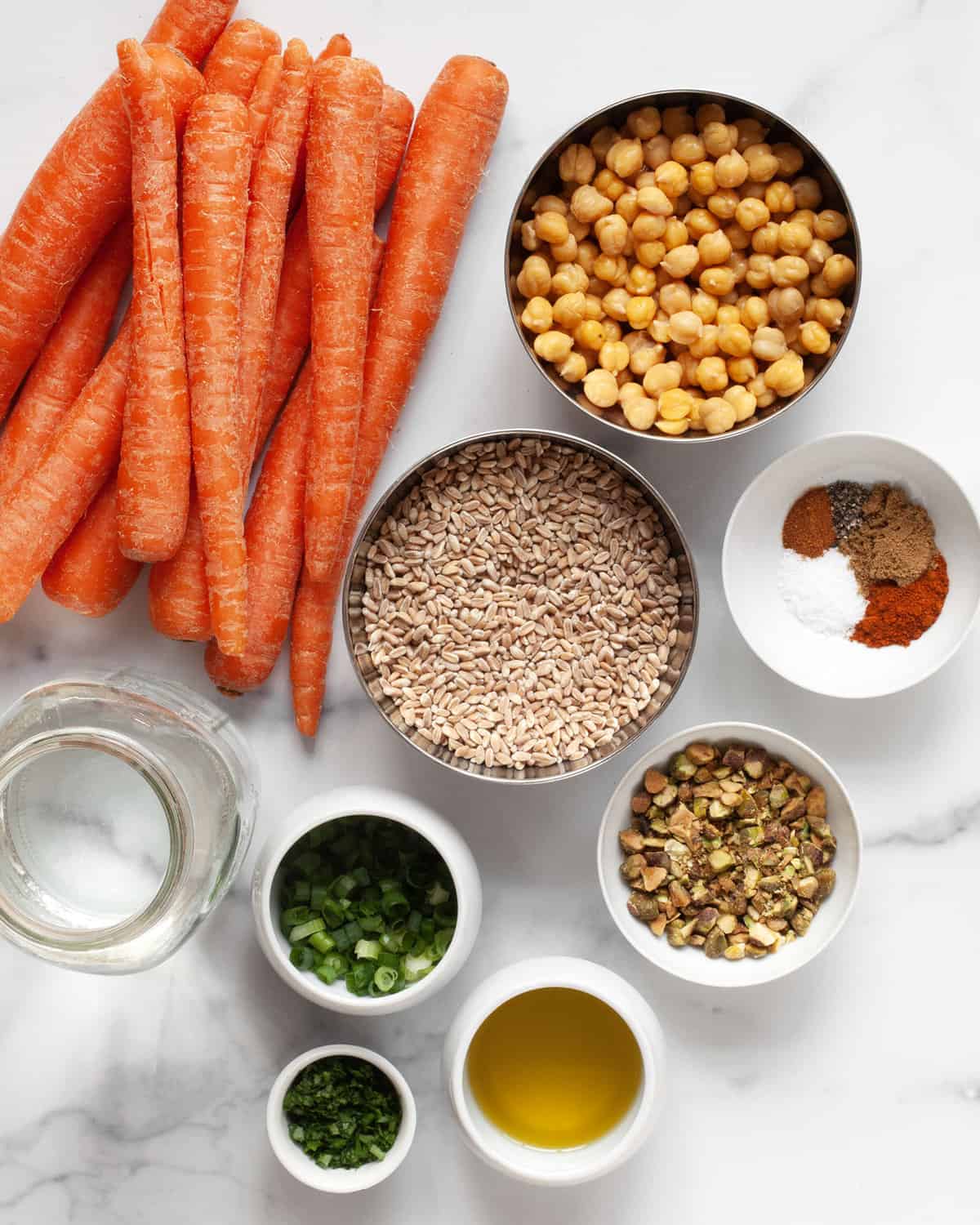 Ingredients including carrots, chickpeas, farro, scallions, parsley, pistachios, olive oil and spices.