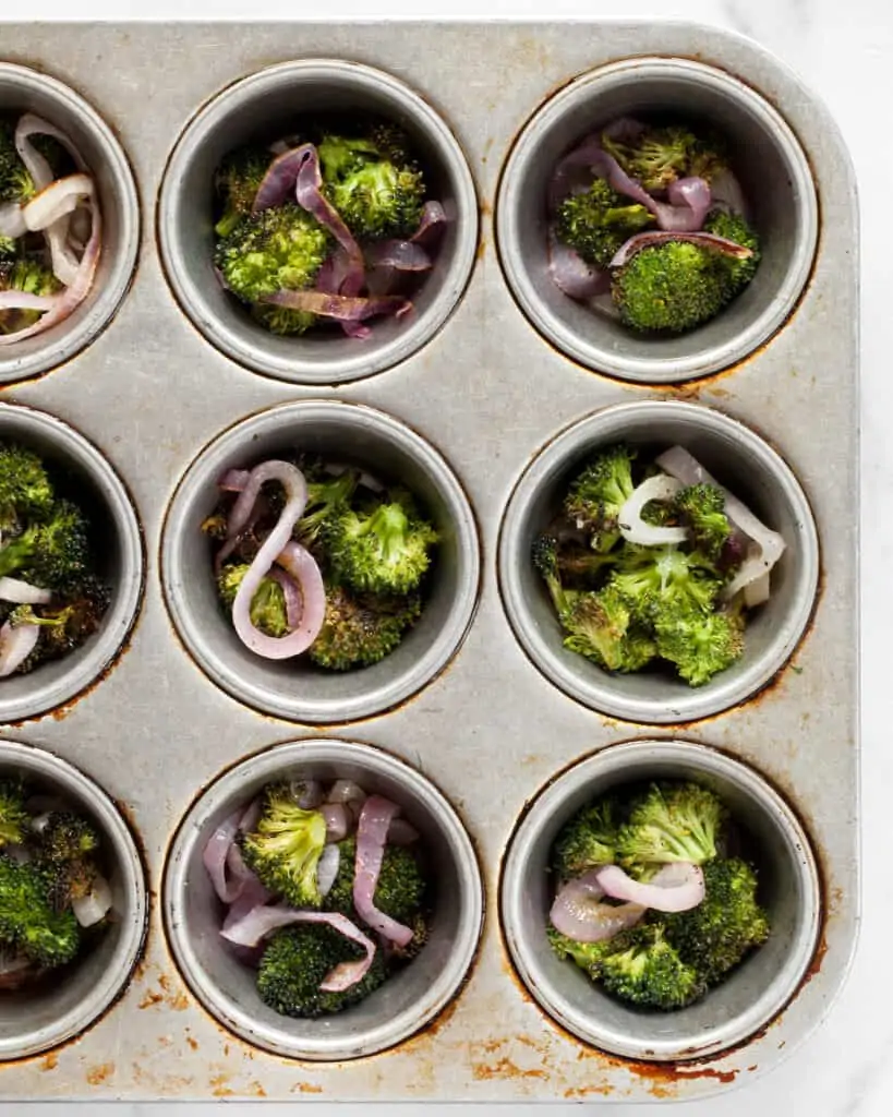 Divide the roasted broccoli and onion into muffin cups