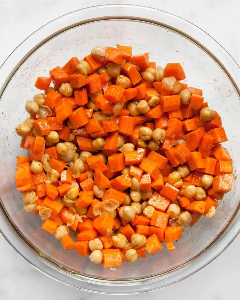 Carrots and chickpeas tossed in spiced olive oil in a bowl