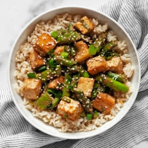 Sesame tofu and asparagus with brown rice in a bowl.