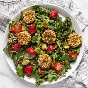 Strawberry salad with pistachio-crusted goat cheese on a plate.
