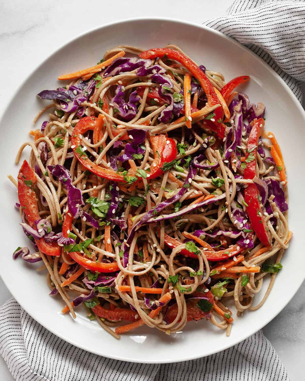 Soba noodle, cabbage, carrot and pepper salad on a plate.