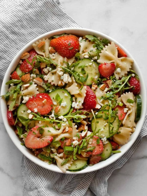 Pasta salad with cucumbers and strawberries in a bowl.