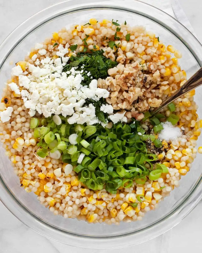 Stirring together the corn, couscous, scallions and other ingredients