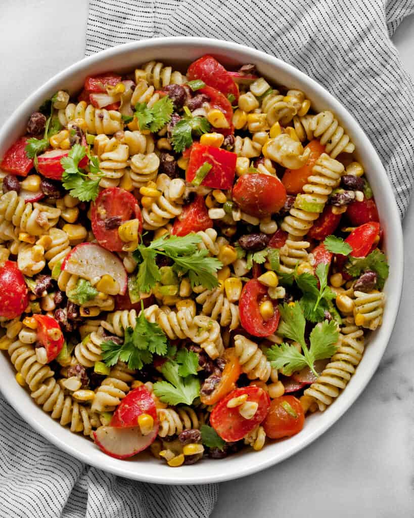 Southwest pasta salad with grilled corn, black beans and radishes in a bowl.