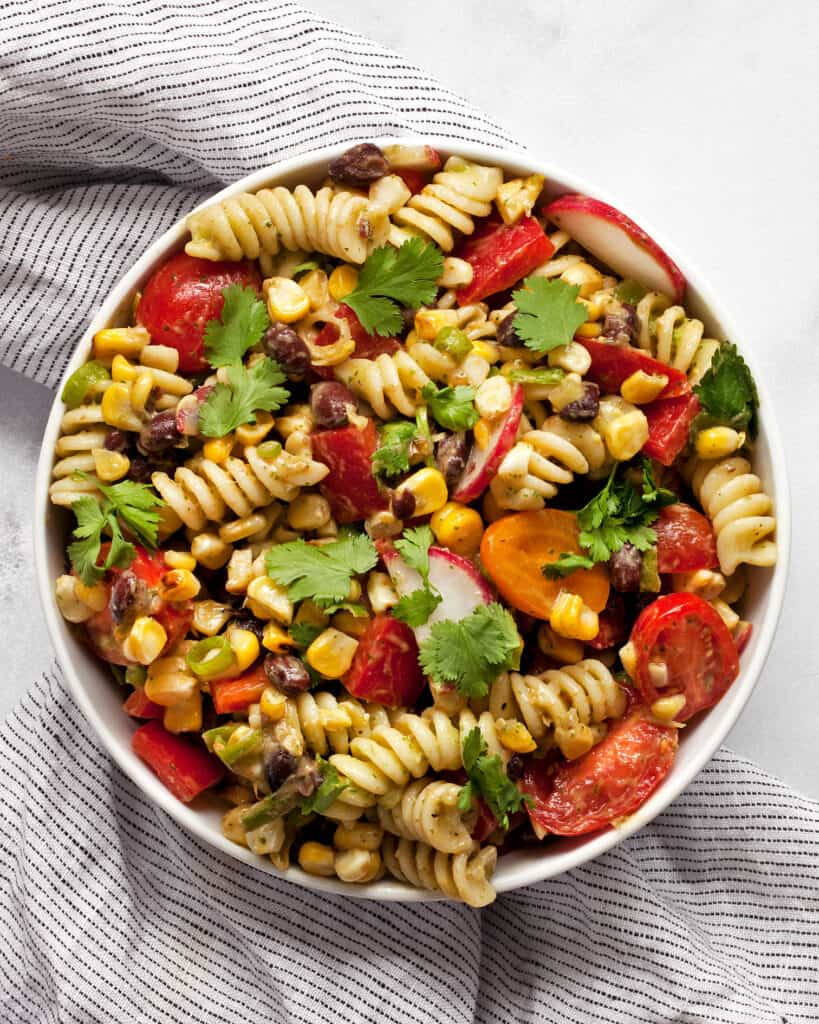 Grilled corn black bean pasta salad with avocado lime dressing in a bowl.