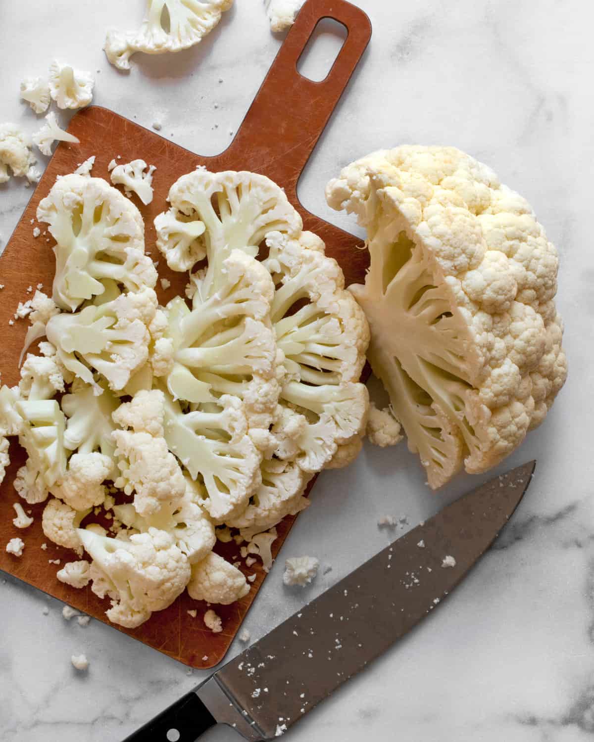 Head of cauliflower sliced on a cutting board.