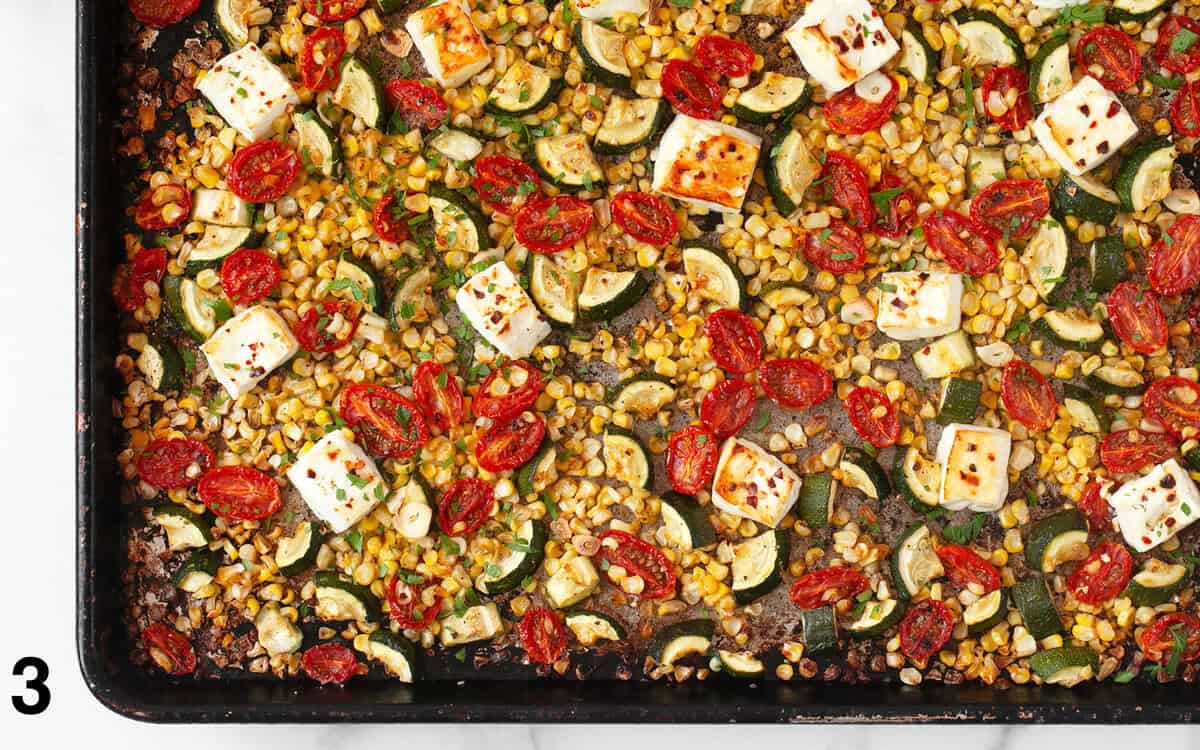 Baked feta and roasted vegetables on a baking sheet.