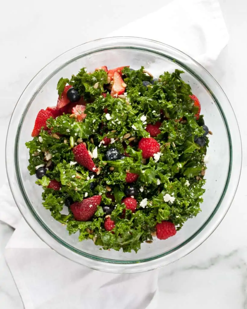 Mixing together berry kale salad in a bowl
