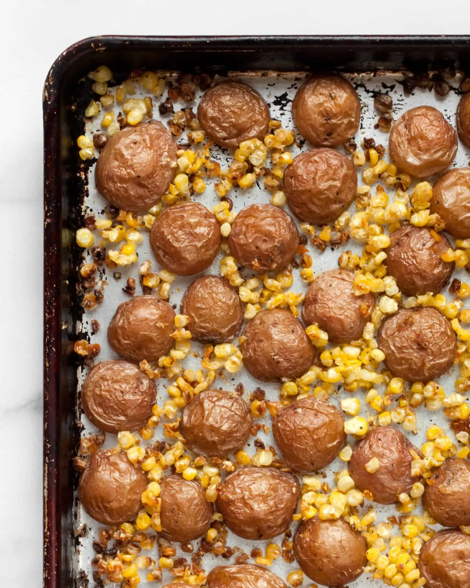 Roasted potatoes and corn on sheet pan