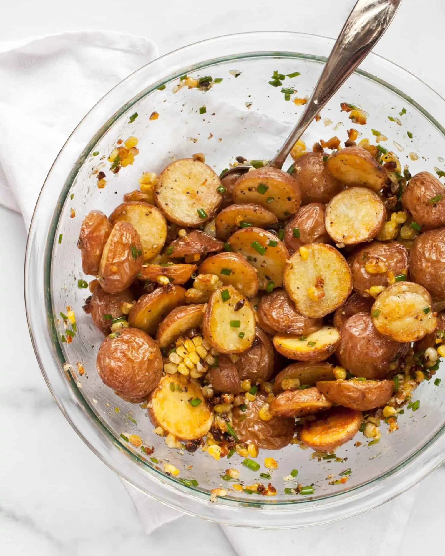 Stirring together roasted potatoes, corn and chive vinaigrette