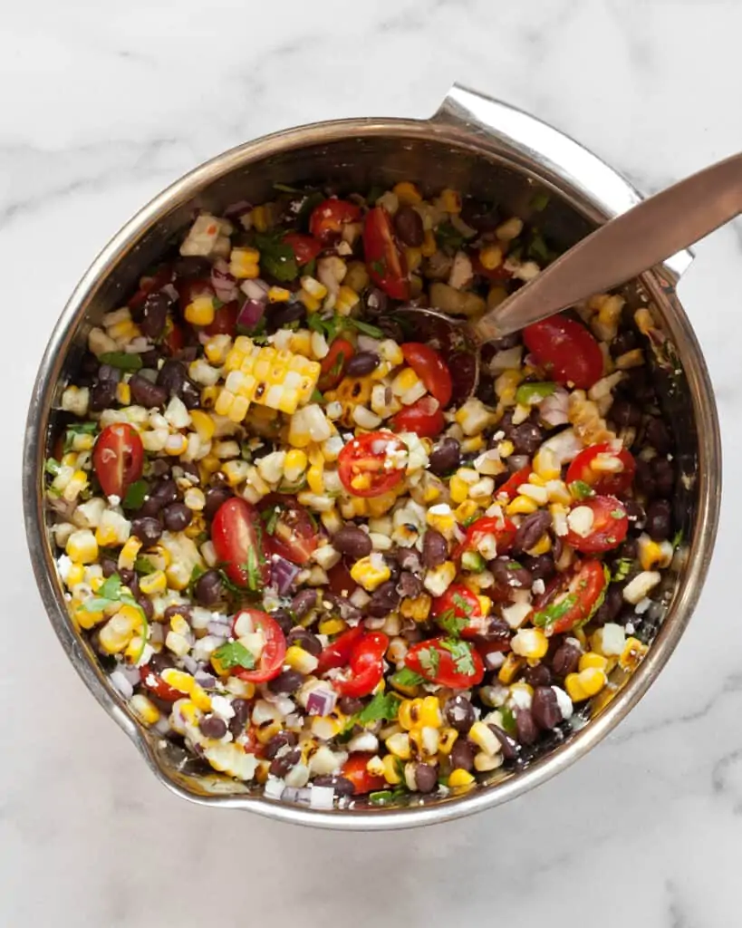 Stirring together salad corn black bean salad ingredients