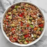 Quinoa salad with chickpeas, roasted tomatoes, cucumber, olives and feta in a large bowl.