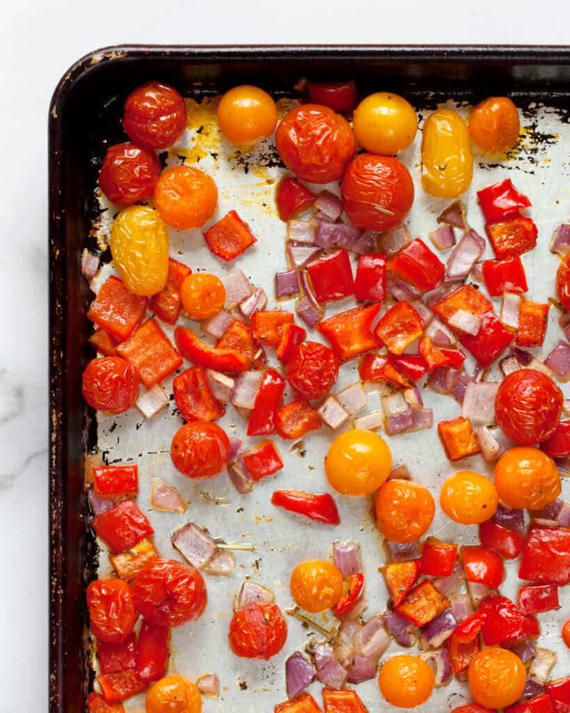 Roasted cherry tomatoes, peppers and onions on a sheet pan