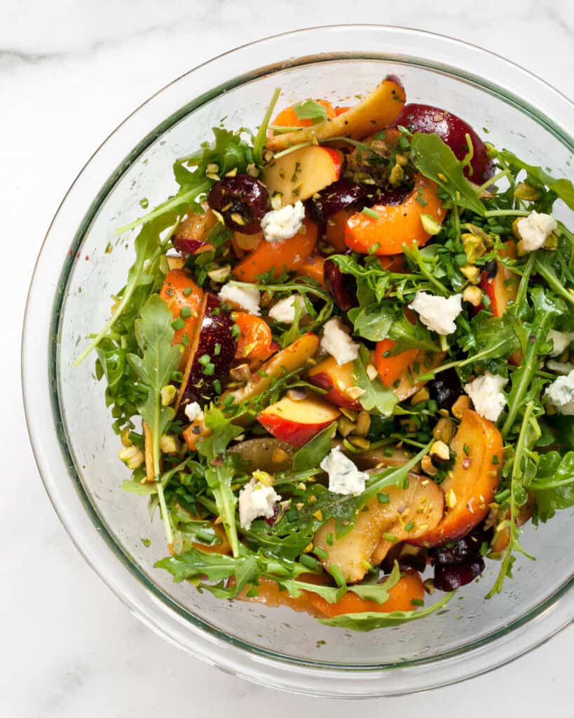 Toss the fruit, greens, cheese and vinaigrette in a bowl