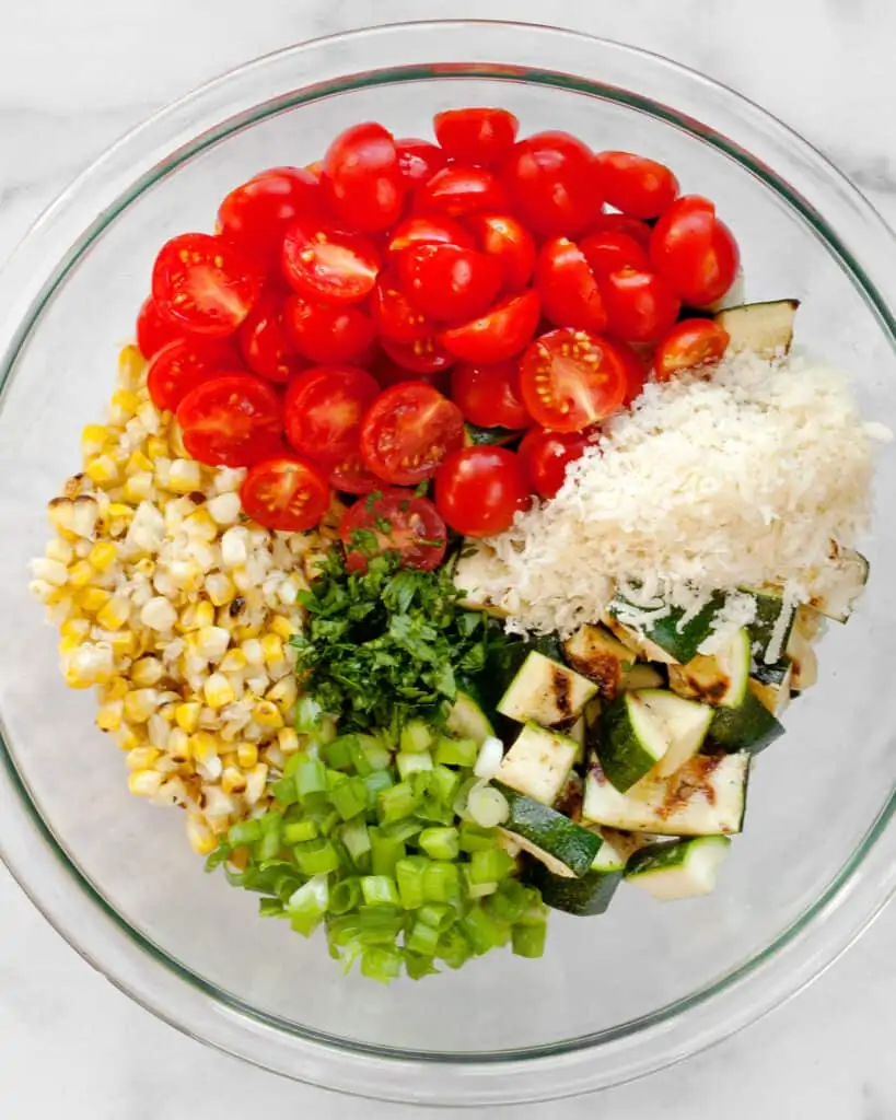 Tomatoes, corn, zucchini, scallions and parmesan in a bowl