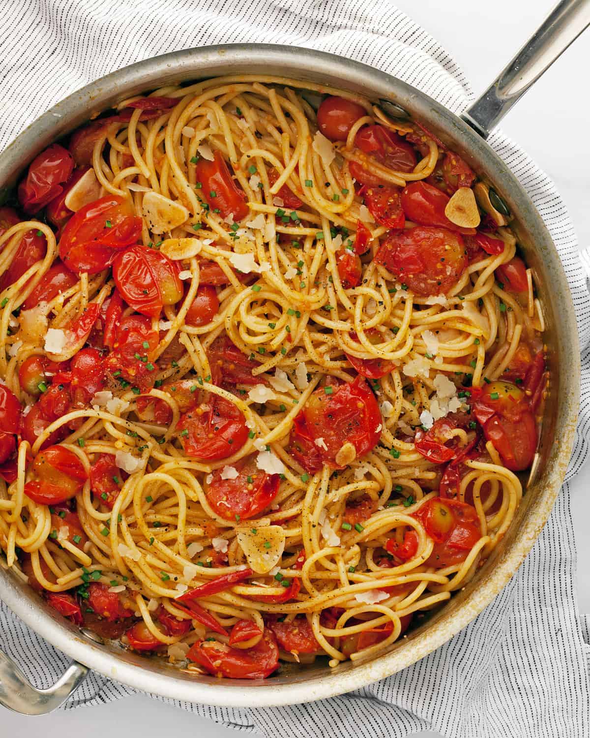 Burst cherry tomato pasta in a skillet.