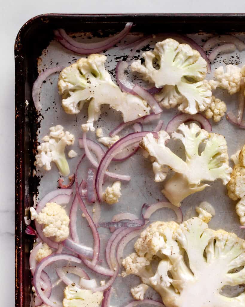 Raw cauliflower and onions on a sheet pan