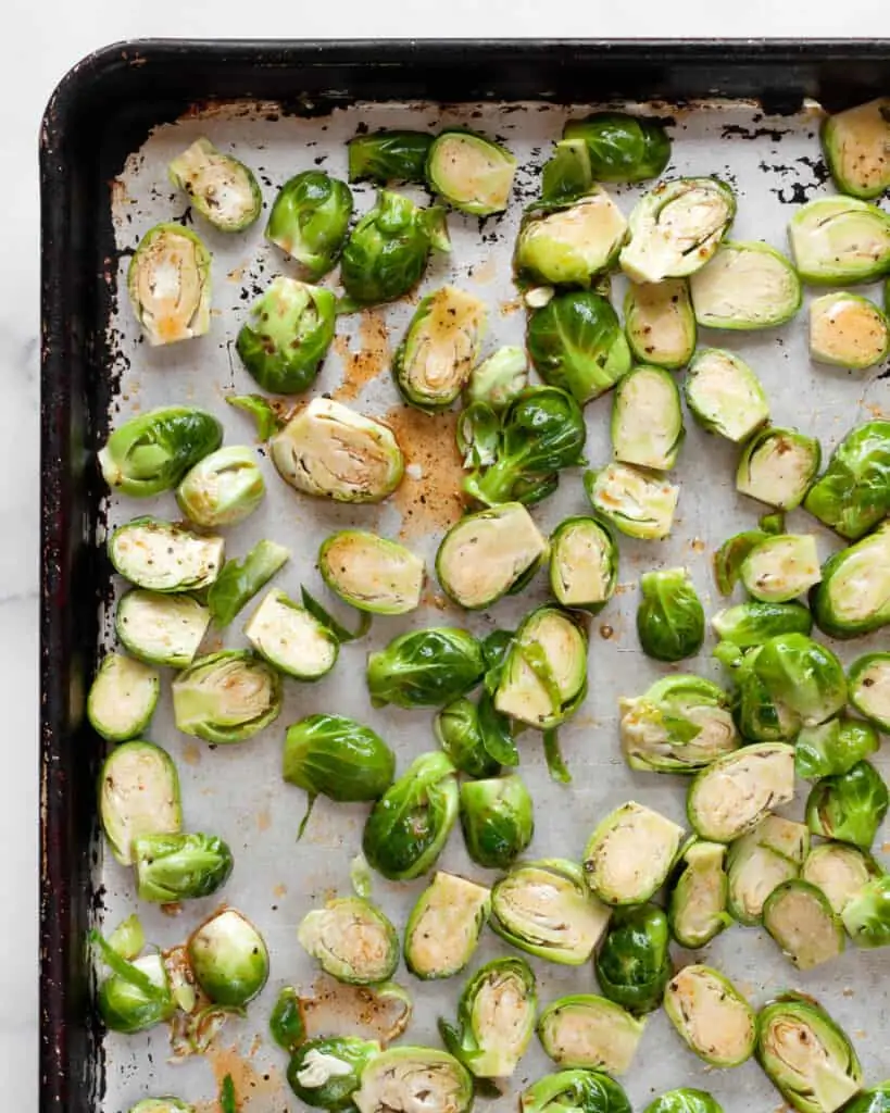 Brussels sprouts tossed with sriracha marinade on a sheet pan