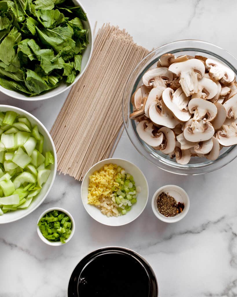 Ingredients including bok choy, mushrooms, soba noodles, scallions, garlic, ginger and spices