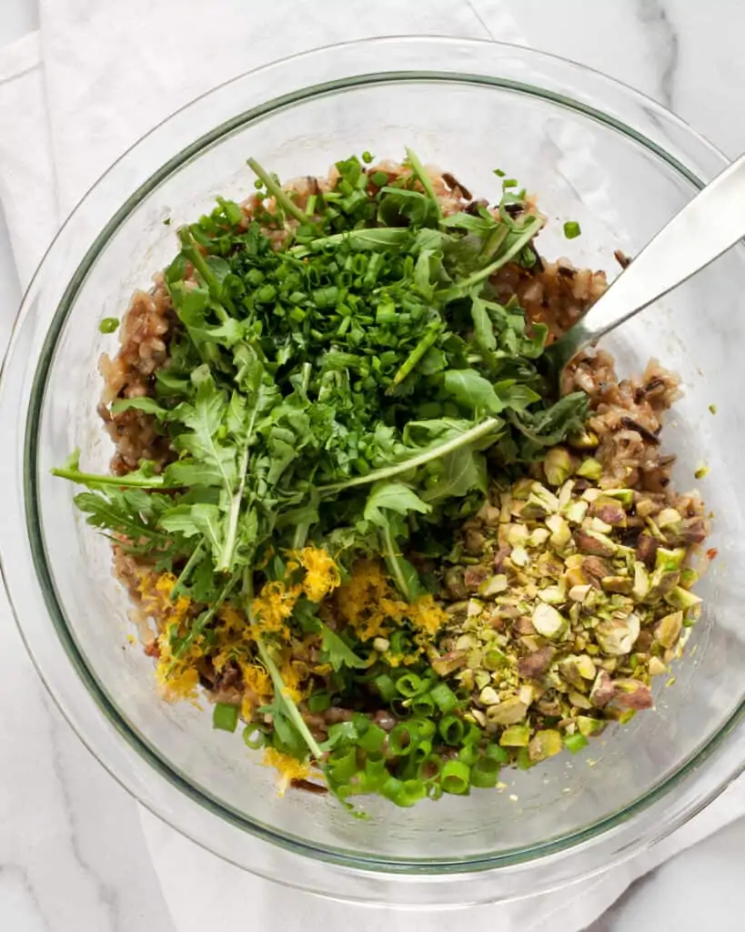 Stirring together the wild rice, arugula and other ingredients