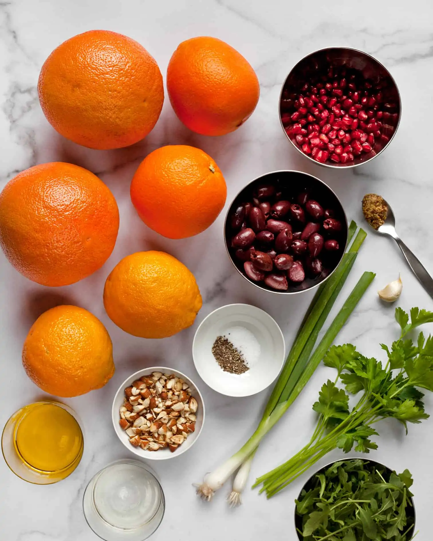 Ingredients including grapefruit, oranges, almonds, olives, pomegranate seeds, and scallions