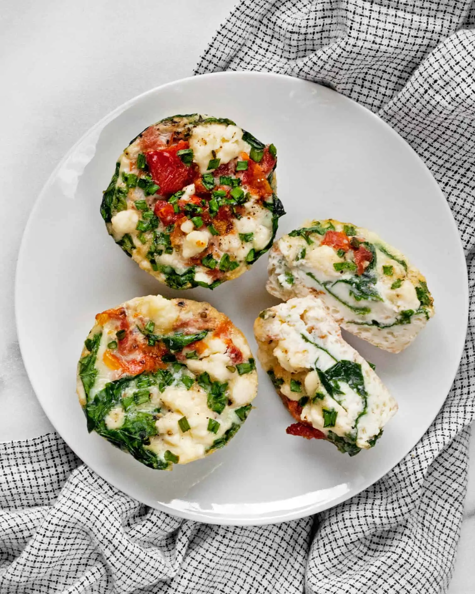 3 spinach feta mini frittatas on a plate with 1 cut in half