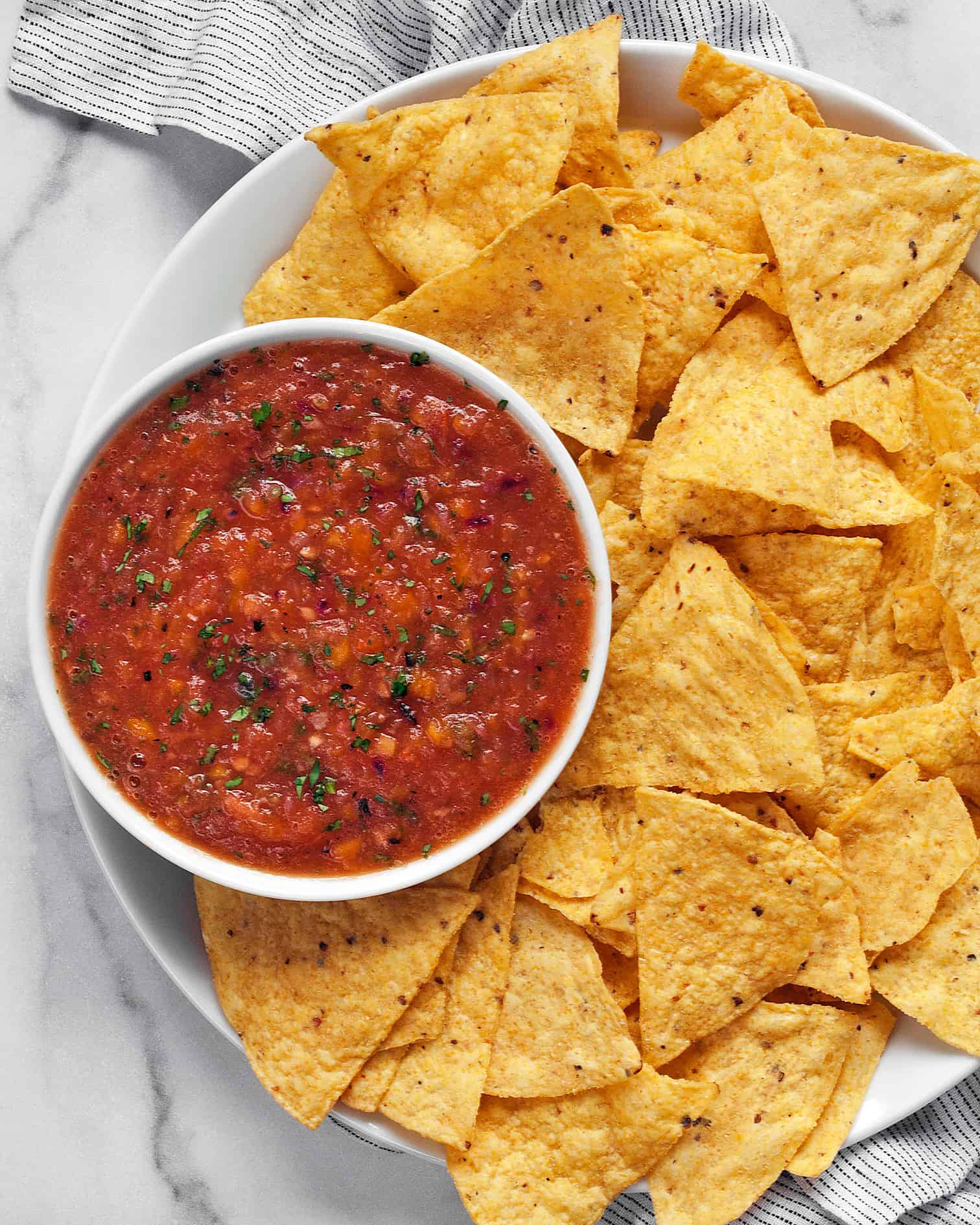 Mango habanero salsa in a bowl with chips on a plate